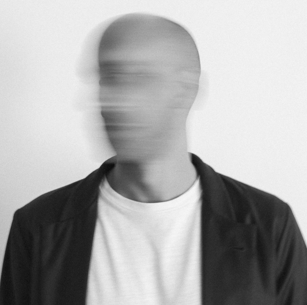 Une image en noir et blanc d'un homme avec une tête floue, suggérant un mouvement rapide, sur un fond blanc.